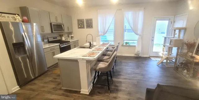 a kitchen with stainless steel appliances a dining table chairs refrigerator and sink