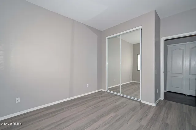a view of an empty room with wooden floor and closet