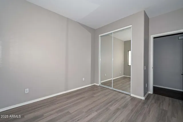 a view of an empty room with wooden floor and closet