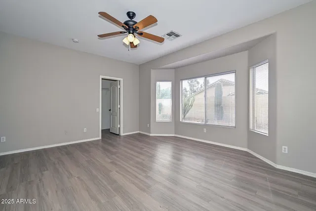 a view of an empty room with a window and wooden floor