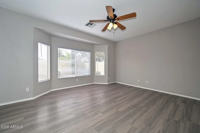 a view of a big room with wooden floor and windows