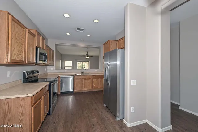 a kitchen with stainless steel appliances granite countertop a refrigerator a sink dishwasher a stove and a wooden cabinets