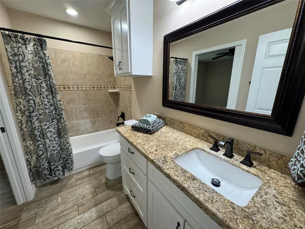 a bathroom with a granite countertop sink toilet and shower