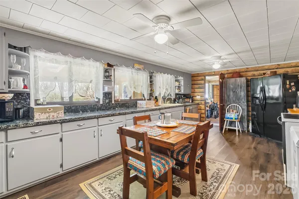 a dining hall with stainless steel appliances granite countertop a stove a sink a dining table and chairs