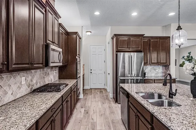 a kitchen with stainless steel appliances granite countertop a sink stove and refrigerator