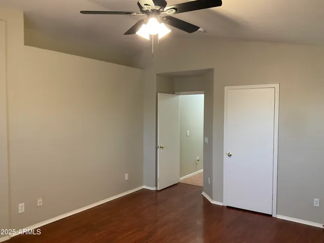 an empty room with wooden floor closet and windows