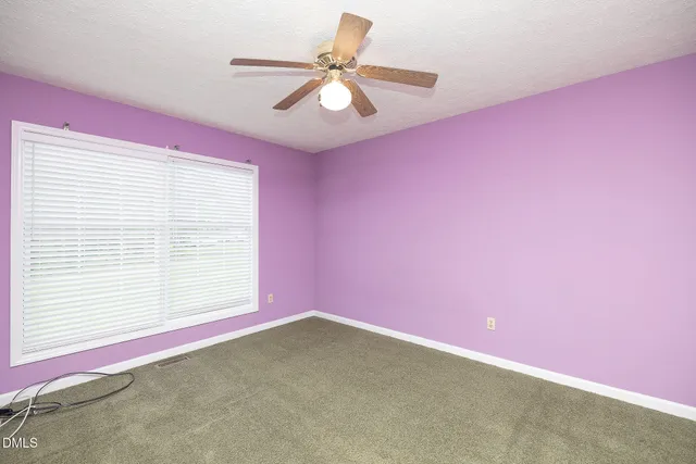 a view of empty room with window and ceiling fan