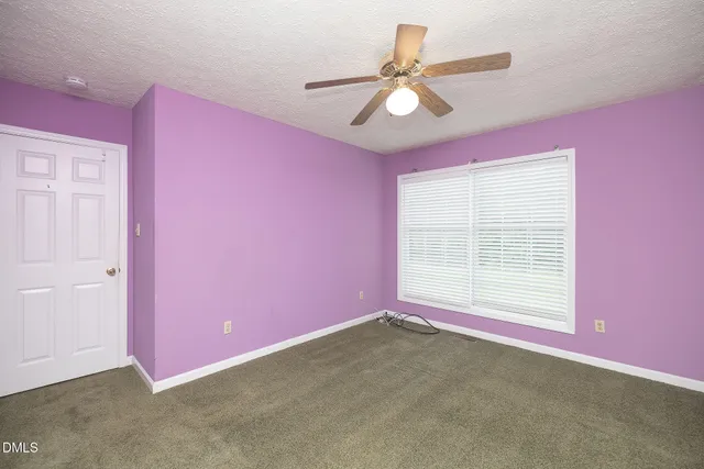 an empty room with a ceiling fan and window