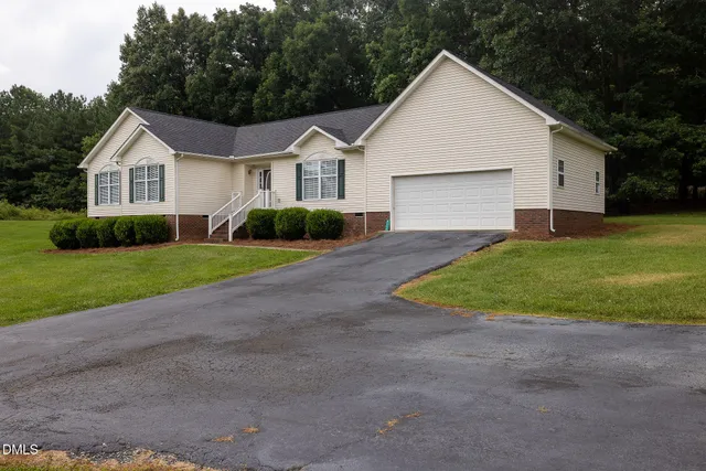 a view of a white house next to a yard and large trees