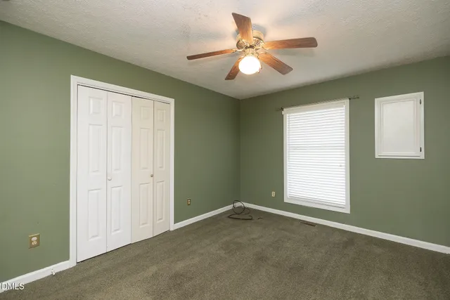 an empty room with closet and fan