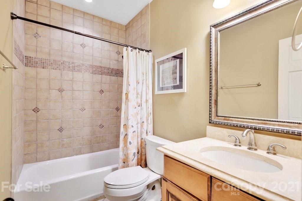 16123 Tana Tea Circle Tega Cay, SC 29708 - Photo 41 of 42 a bathroom with a granite countertop sink a toilet a mirror a bathtub and shower