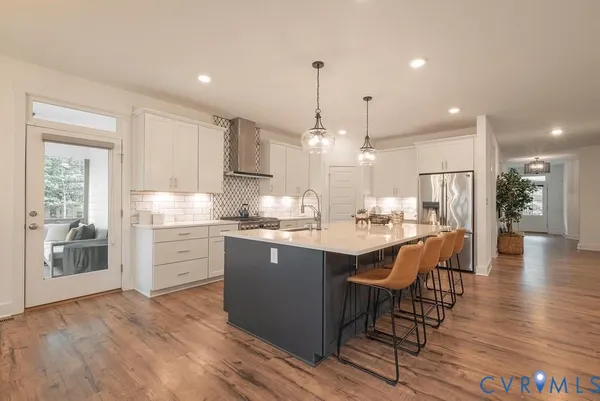 a kitchen with stainless steel appliances kitchen island granite countertop a table chairs and a refrigerator