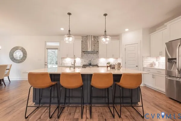 a kitchen with stainless steel appliances granite countertop a dining table chairs stove and white cabinets