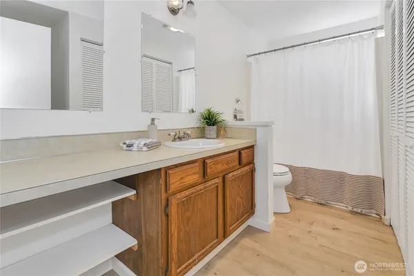 a bathroom with a sink a toilet a mirror and shower