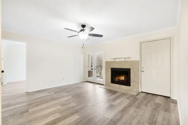 a view of an empty room with wooden floor fireplace and a window
