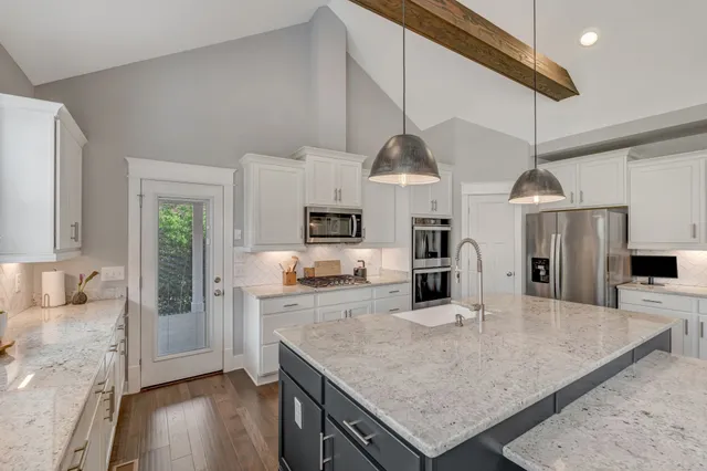 a kitchen with stainless steel appliances granite countertop a sink a stove and a refrigerator