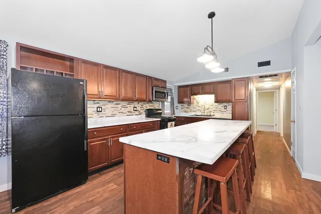 a kitchen with stainless steel appliances granite countertop a refrigerator a sink dishwasher a stove with wooden floor