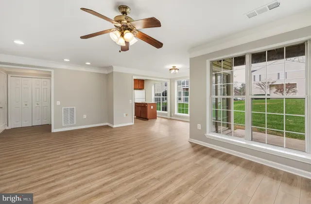 a view of an empty room with a window and wooden floor