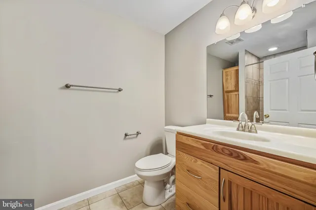a bathroom with a granite countertop toilet sink mirror and vanity