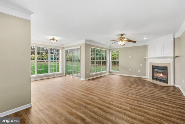 a view of an empty room with wooden floor fireplace and a window
