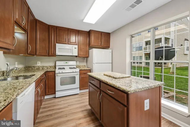 a kitchen with granite countertop wooden cabinets and a stove