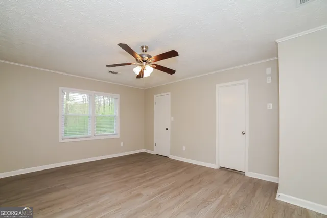 an empty room with wooden floor and windows
