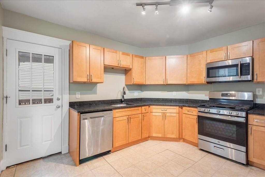 4 Bailey Street, Unit 1 Boston, MA 02124 - Photo 6 of 11 a kitchen with granite countertop a stove top oven sink and cabinets