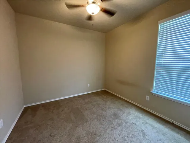 an empty room with a chandelier fan and windows