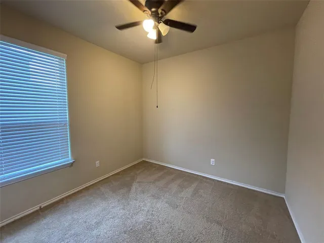 an empty room with a window and a fan