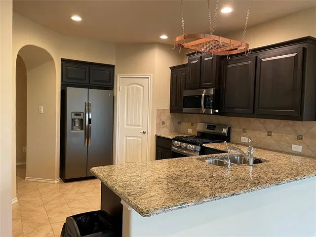 a kitchen with stainless steel appliances granite countertop a sink refrigerator and microwave