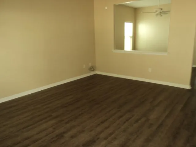 a view of an empty room with wooden floor and a window