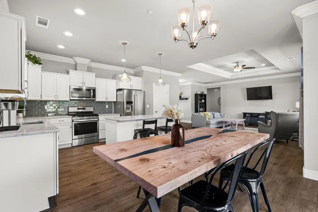 a kitchen with stainless steel appliances kitchen island granite countertop a stove a sink a refrigerator a kitchen island and chairs with wooden floor