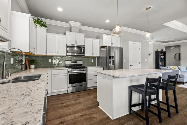 a kitchen with a stove a counter space a sink dishwasher and a dining table with wooden floor