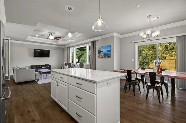 a kitchen with kitchen island granite countertop a refrigerator a stove a sink and white cabinets with wooden floor