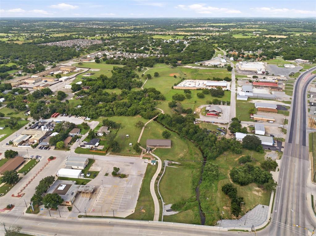 308 West 1st Street Springtown, TX 76082 - Photo 38 of 39 Expansive aerial view showcasing a mixed-use landscape with commercial buildings, residential properties, and abundant green spaces