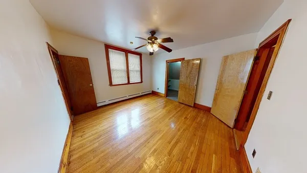 a view of an empty room with window and wooden floor