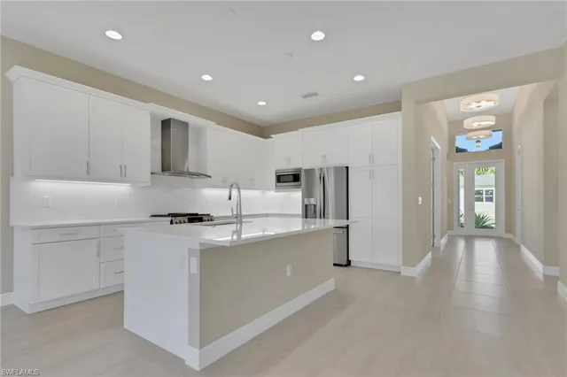 a kitchen with stainless steel appliances a stove a sink a refrigerator and white cabinets