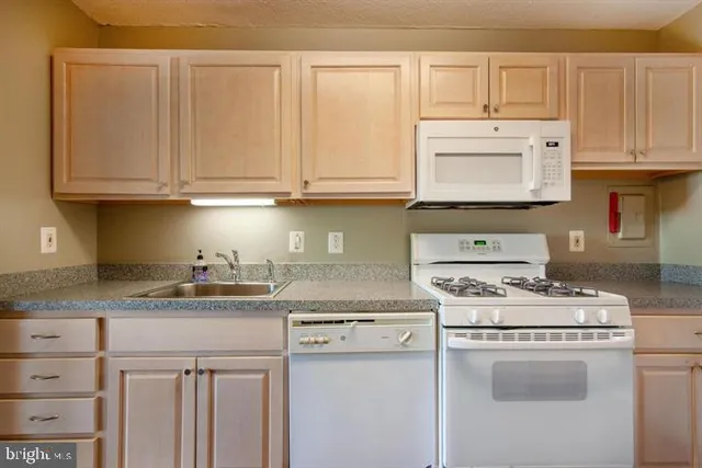 a kitchen with granite countertop white cabinets and white appliances