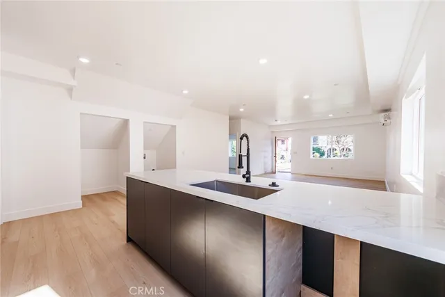 a kitchen with kitchen island a sink and a stove top oven with wooden floor