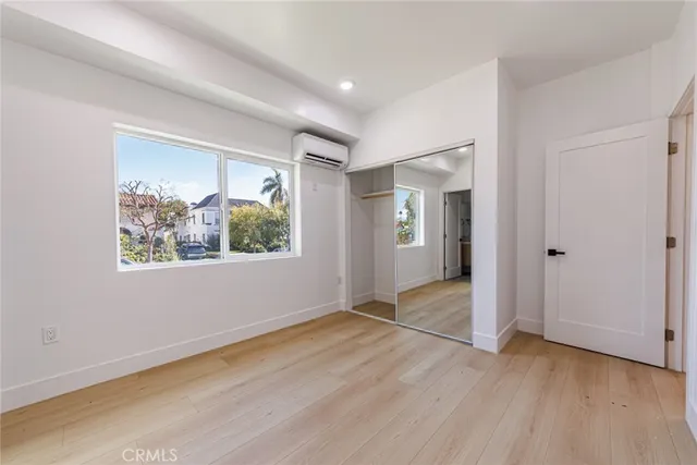 a view of an empty room with wooden floor and window