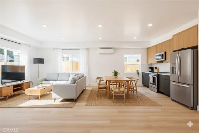 a living room with furniture a flat screen tv and a refrigerator