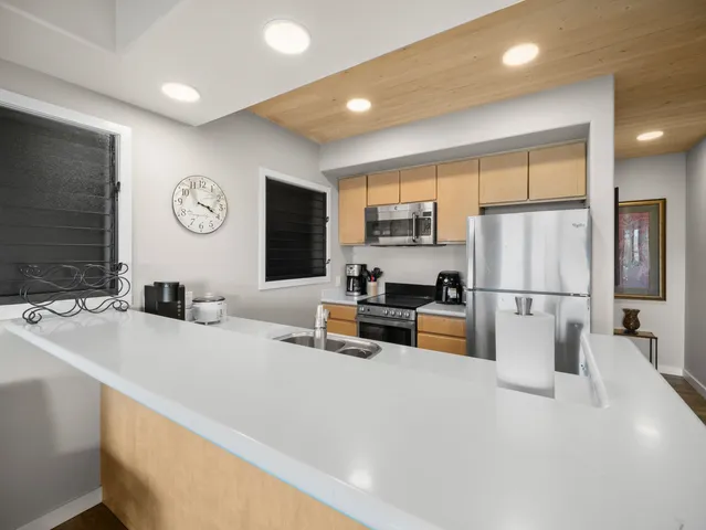 a kitchen with stainless steel appliances a refrigerator a stove a sink a oven with white cabinets and wooden floor