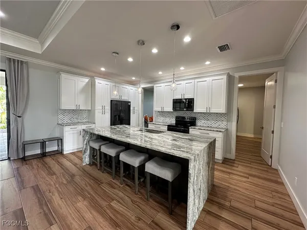 a large kitchen with stainless steel appliances granite countertop a lot of counter space and wooden floors