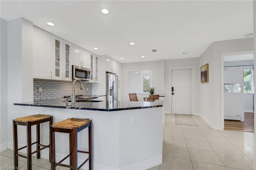 7766 Emerald Circle, Unit R203 Naples, FL 34109 - Photo 9 of 25 a kitchen with stainless steel appliances granite countertop a stove a sink a microwave a refrigerator and cabinets
