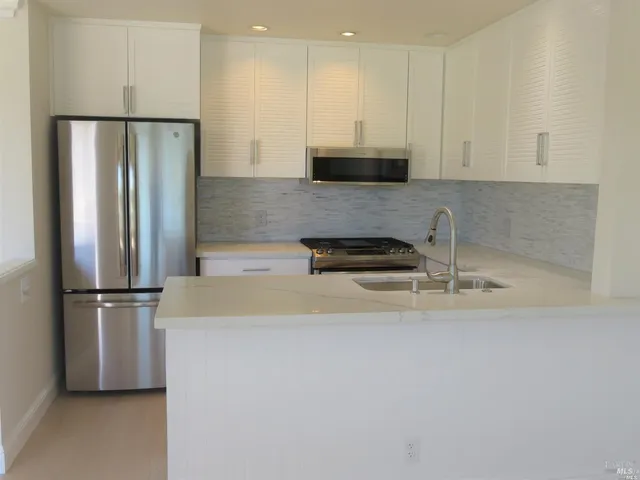 a kitchen with stainless steel appliances granite countertop a refrigerator a stove a sink and a refrigerator