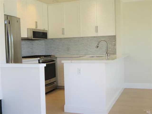 a kitchen with stainless steel appliances granite countertop a refrigerator a stove and a sink