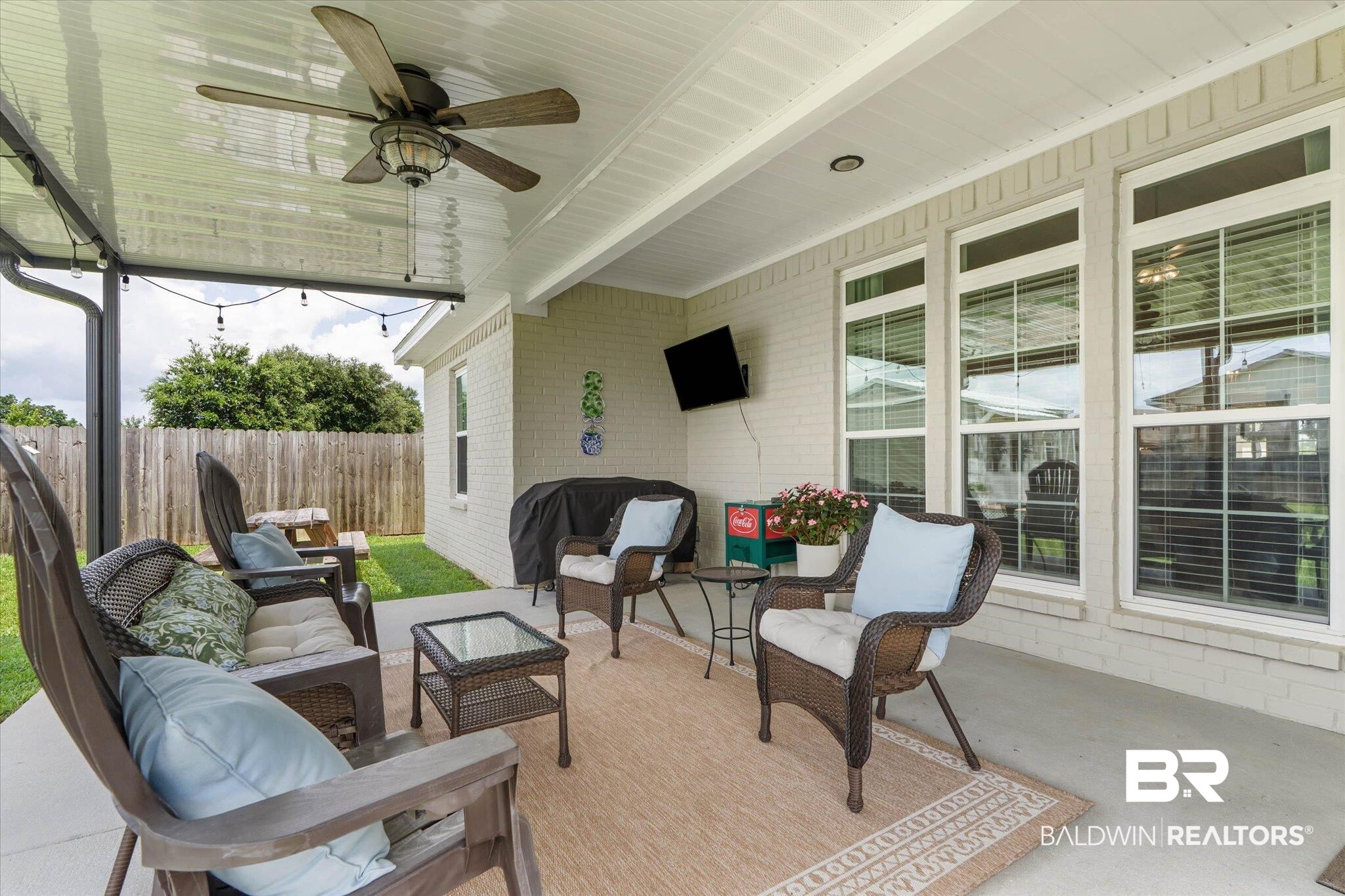 9074 Moses Way Theodore, AL 36582 - Photo 43 of 52 Covered patio area featuring a ceiling fan, string lights, and three large windows with blinds