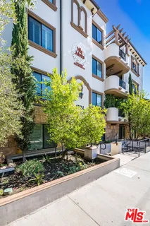 a front view of a multi story residential apartment building with yard and bench