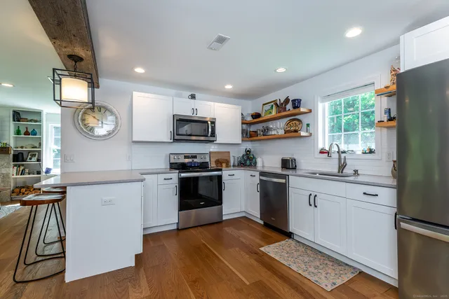 a kitchen with stainless steel appliances granite countertop a refrigerator oven a sink dishwasher and a stove with wooden floor