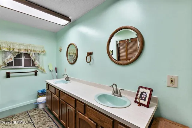 a bathroom with a granite countertop double vanity sink and a mirror